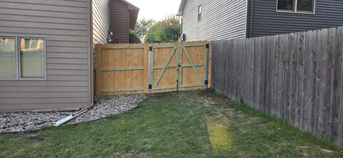 Wood gate between houses with metal support posts